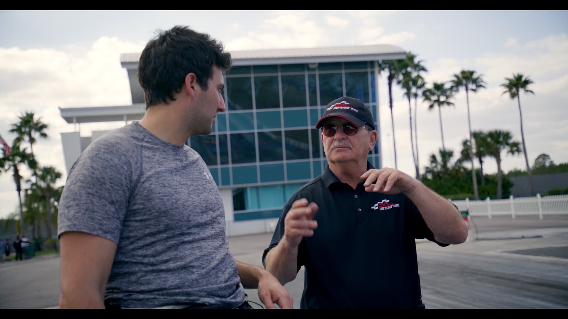 Host talking with a racing instructor at a motorsport school